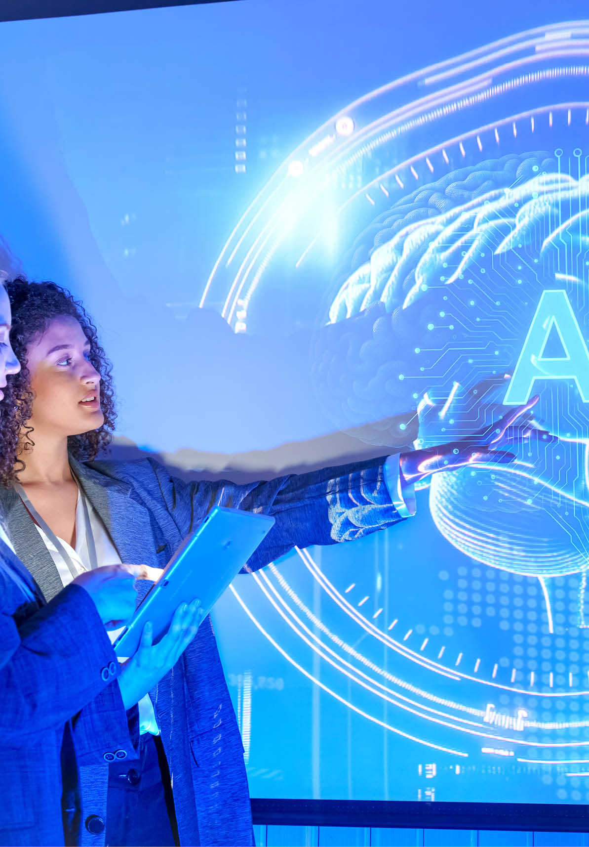 Two women engage in a discussion about artificial intelligence, with a digital brain image projected behind them. They are in a modern setting, highlighting the importance of technology.