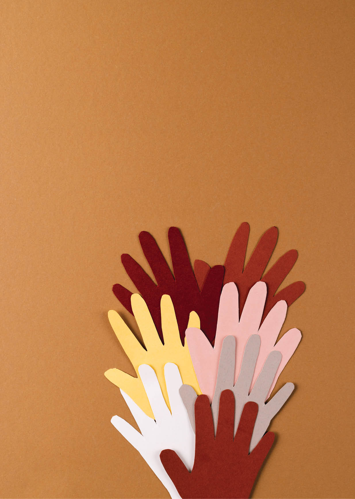 Paper cut out of multi coloured hands with copy space on brown background. Humanitarian aid, people, help and human concept.