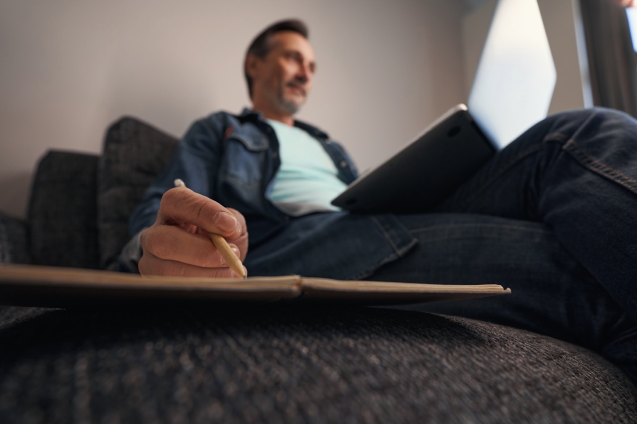 Male working online and making notes with pen